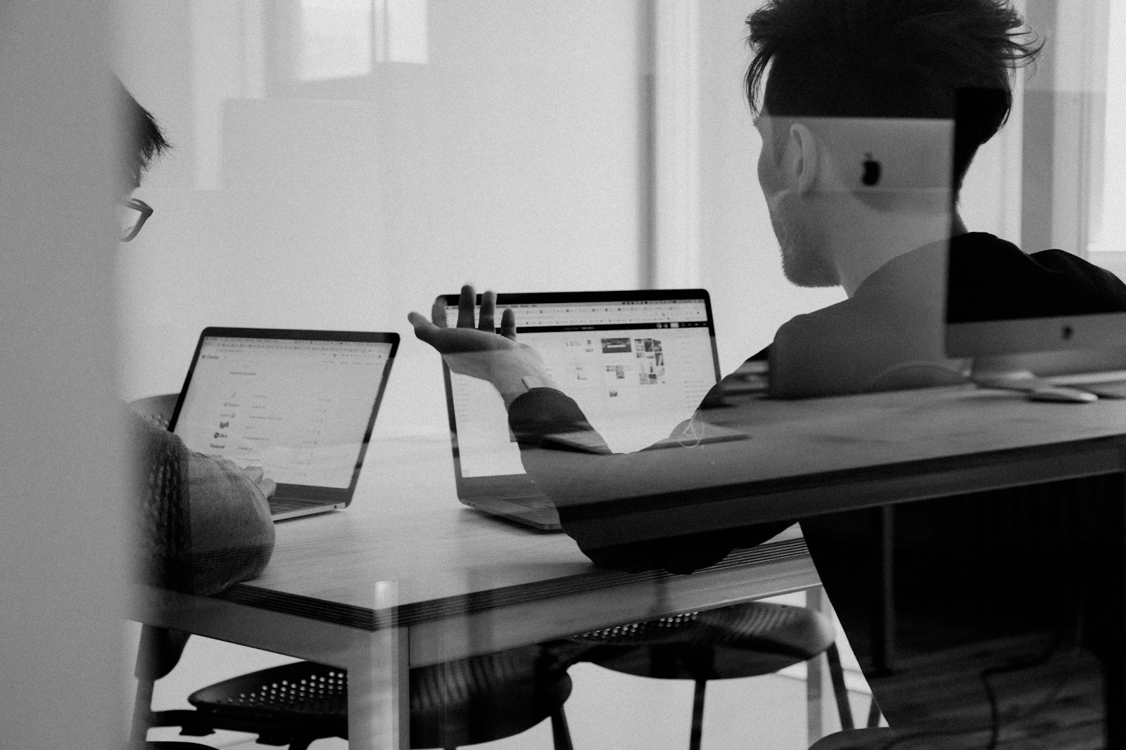 To kollegaer som diskuterer Google-rangering og SEO foran laptoper